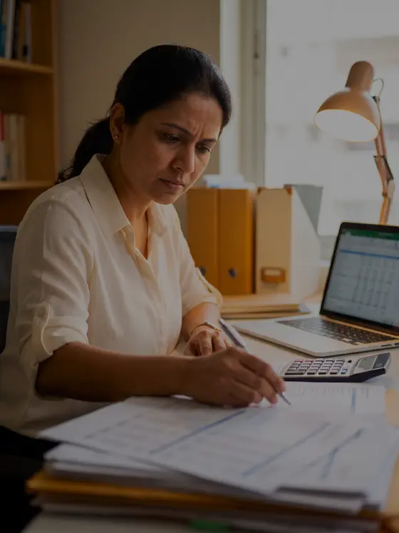 A chartered accountant checking a column of figures on printed statements beside a calculator