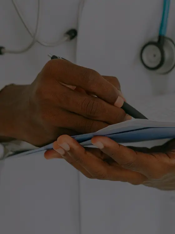A doctor in a white coat annotating a patient chart, stethoscope at the collar