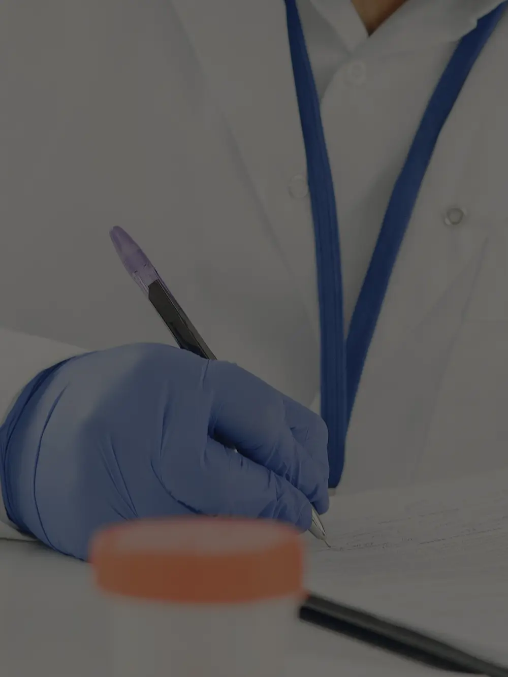A gloved hand writing notes onto a printed page at a lab bench